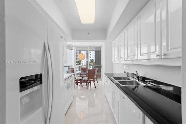 kitchen with white appliances, white cabinetry, and sink