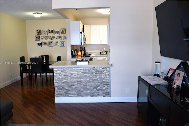 kitchen featuring black electric range, kitchen peninsula, white cabinetry, and dark wood-type flooring