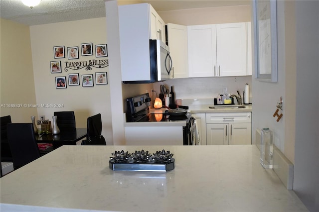 kitchen with stainless steel appliances, white cabinetry, sink, and a textured ceiling