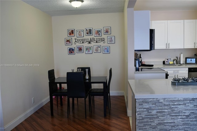 dining space featuring a textured ceiling, sink, and dark hardwood / wood-style flooring