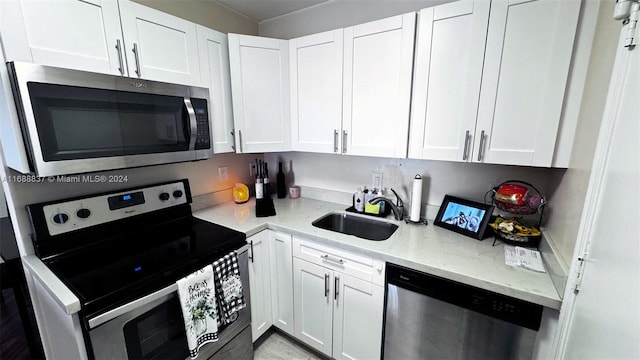 kitchen with stainless steel appliances, white cabinets, and sink