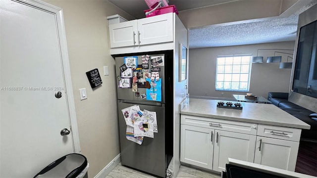 kitchen with white cabinets, stainless steel fridge, and a textured ceiling