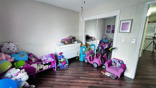 playroom with dark wood-type flooring and a textured ceiling