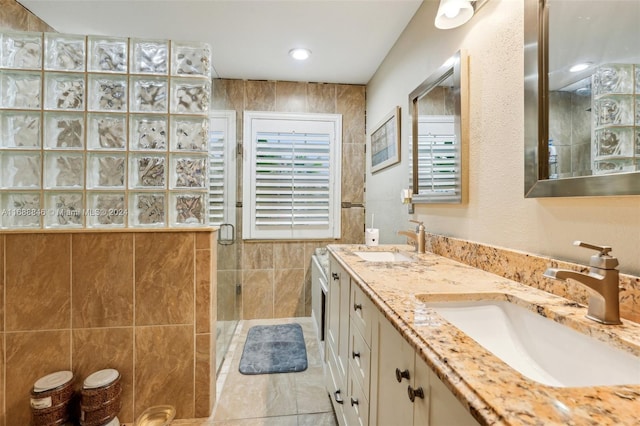 bathroom with tile walls, vanity, tile patterned floors, and a shower with shower door