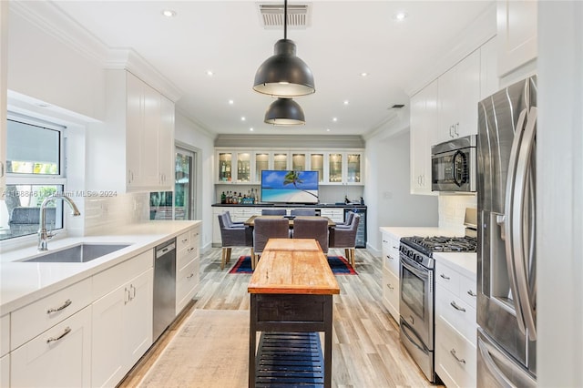 kitchen with white cabinetry, sink, a healthy amount of sunlight, hanging light fixtures, and appliances with stainless steel finishes