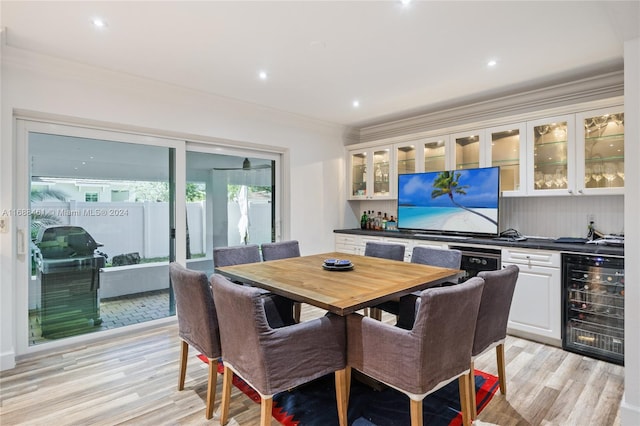 dining space with bar area, light wood-type flooring, wine cooler, and crown molding