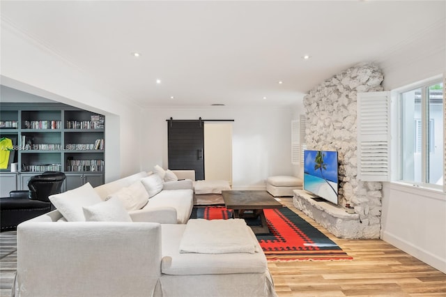 living room featuring a barn door, wood-type flooring, and ornamental molding