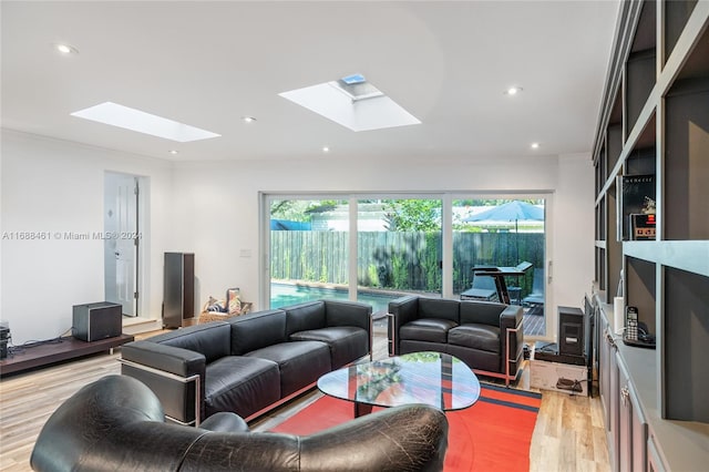 living room with a skylight, light hardwood / wood-style flooring, and crown molding