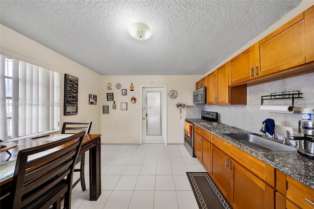 kitchen featuring dark stone counters, black / electric stove, sink, and a textured ceiling