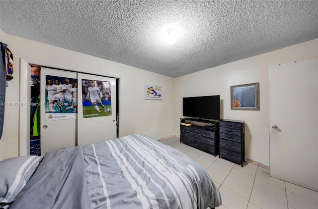 bedroom with a closet, a textured ceiling, and light tile patterned floors