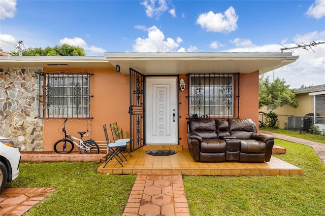 view of exterior entry with central AC unit and a lawn