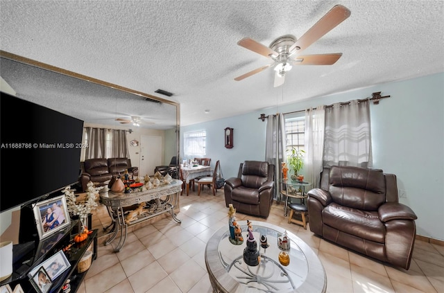 living room with a textured ceiling, ceiling fan, and light tile patterned floors