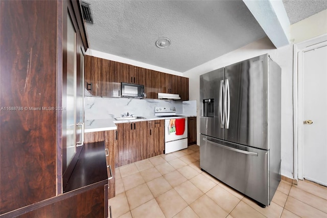 kitchen with refrigerator, stainless steel fridge, a textured ceiling, tasteful backsplash, and white range with electric stovetop