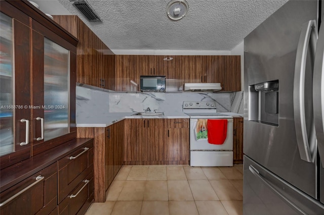 kitchen with white electric range oven, decorative backsplash, a textured ceiling, sink, and stainless steel fridge