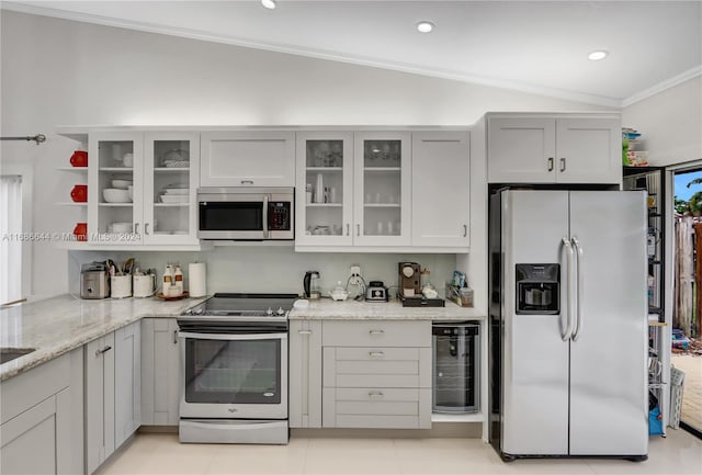 kitchen with stainless steel appliances, light stone counters, vaulted ceiling, light tile patterned floors, and crown molding