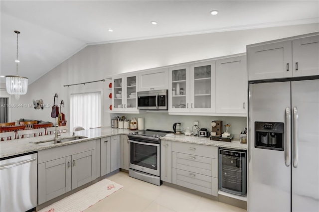 kitchen featuring stainless steel appliances, lofted ceiling, beverage cooler, hanging light fixtures, and sink