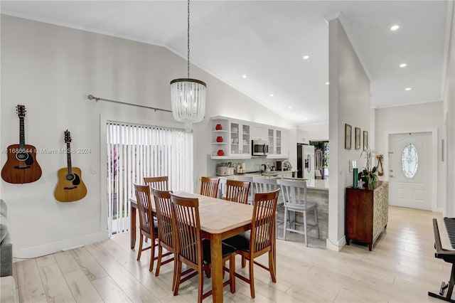 dining area with high vaulted ceiling, light hardwood / wood-style flooring, a notable chandelier, and crown molding