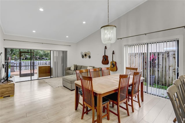 dining room featuring light wood-type flooring, lofted ceiling, a chandelier, and crown molding