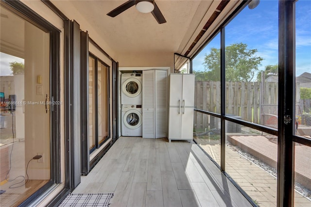 unfurnished sunroom with stacked washer / dryer, ceiling fan, and plenty of natural light