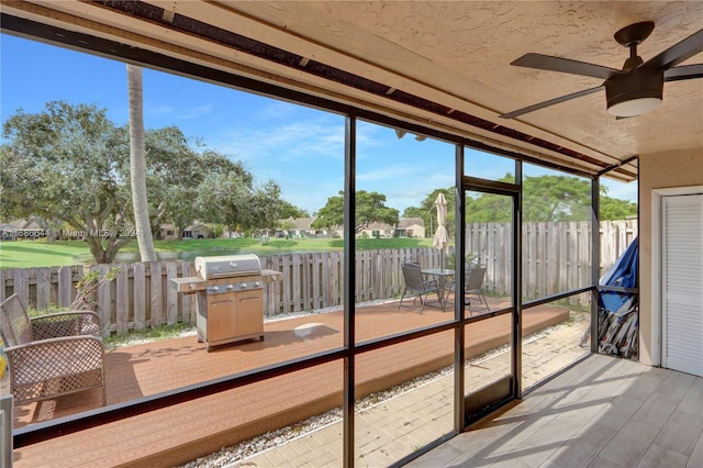 unfurnished sunroom with ceiling fan