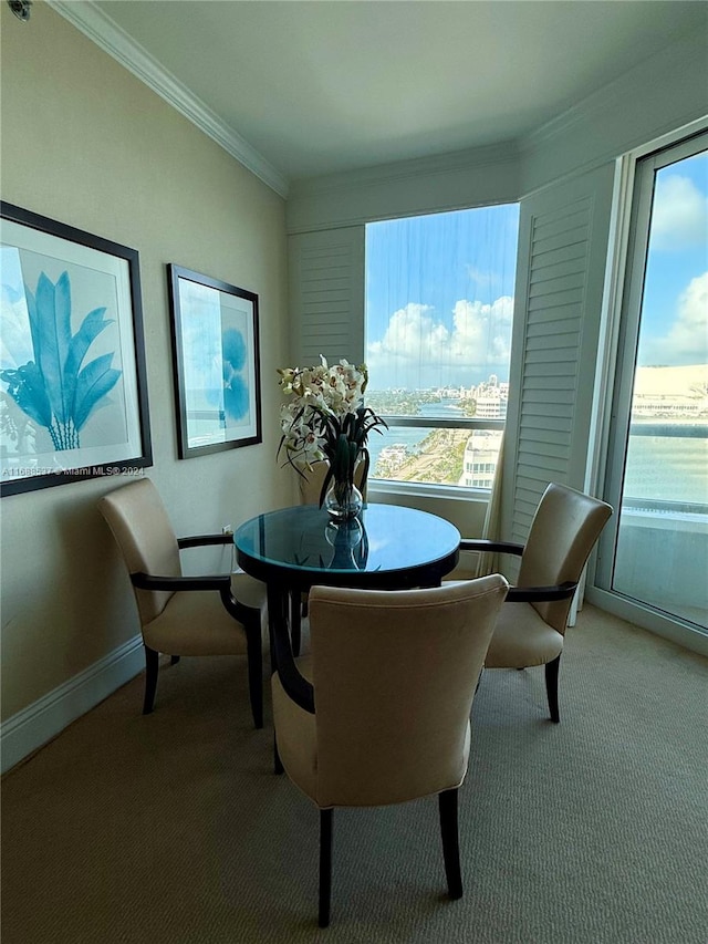 dining space featuring light carpet, a water view, and crown molding