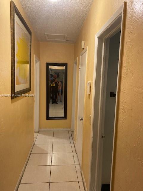 hallway featuring a textured ceiling and light tile patterned floors