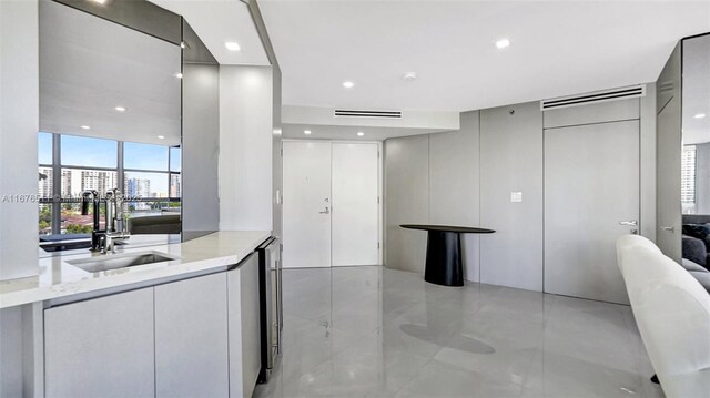 kitchen featuring stainless steel built in fridge, light stone counters, gray cabinets, black electric cooktop, and wall chimney exhaust hood