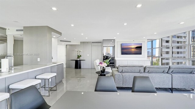 kitchen featuring stainless steel appliances, wall chimney range hood, gray cabinetry, and light stone countertops