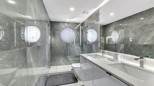 bathroom featuring walk in shower, vanity, toilet, and tile walls