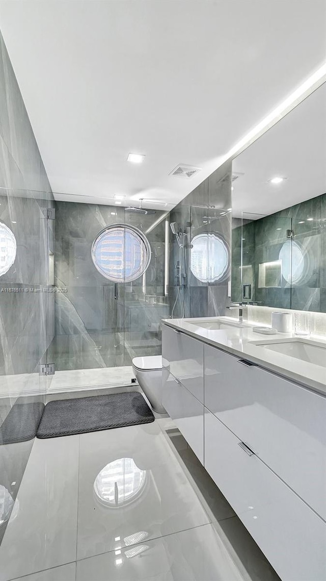 bathroom featuring tile walls, vanity, toilet, and a shower with shower door