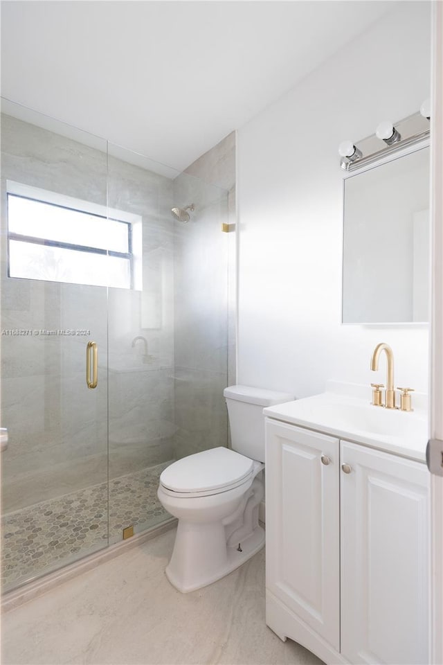 bathroom featuring vanity, toilet, and a shower with door