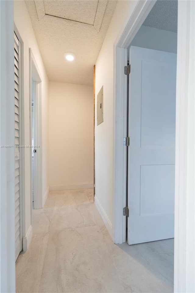 corridor with a textured ceiling and electric panel