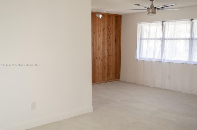 empty room with a textured ceiling, ceiling fan, and wooden walls