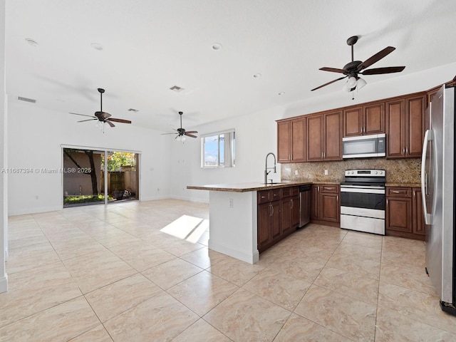 kitchen featuring sink, light tile patterned floors, kitchen peninsula, stainless steel appliances, and backsplash