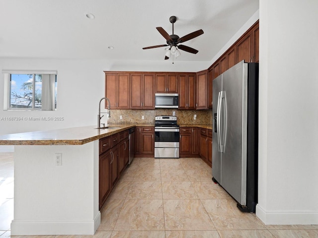 kitchen with sink, tasteful backsplash, kitchen peninsula, ceiling fan, and stainless steel appliances