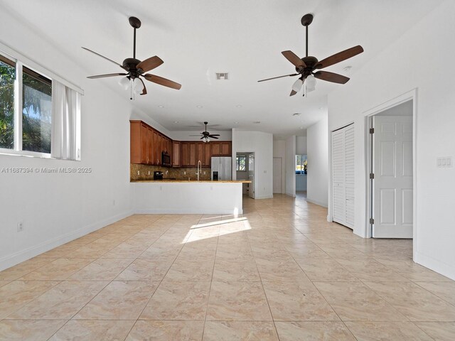 kitchen with stainless steel appliances, kitchen peninsula, sink, backsplash, and light stone countertops