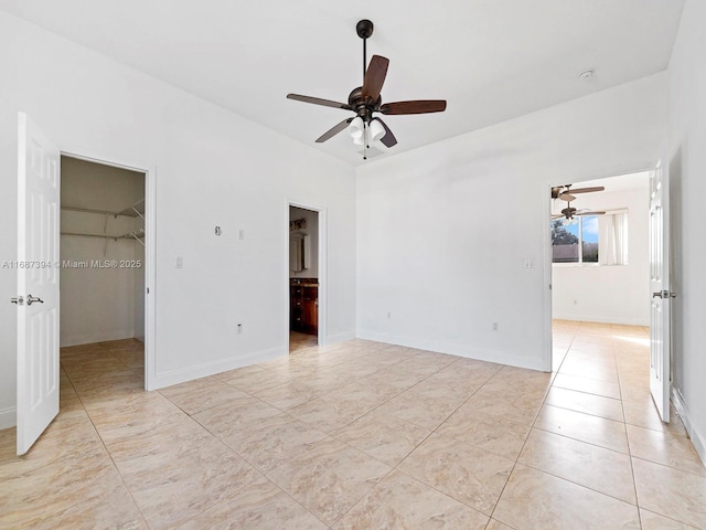 unfurnished bedroom with connected bathroom, a spacious closet, light tile patterned floors, ceiling fan, and a closet