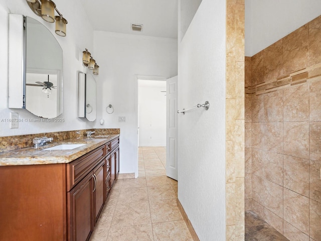 bathroom featuring tile patterned flooring, vanity, tiled shower, and ceiling fan