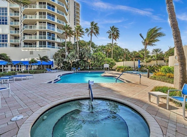 view of pool with a hot tub and a patio