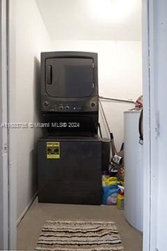 laundry room with water heater and stacked washer / drying machine