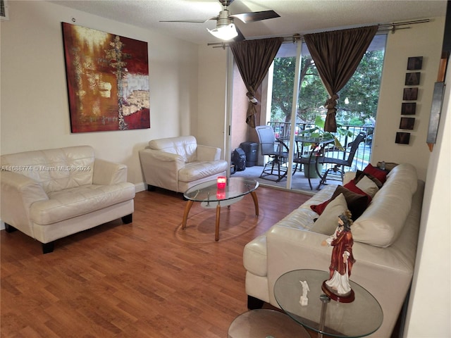 living room featuring wood-type flooring, ceiling fan, and a textured ceiling