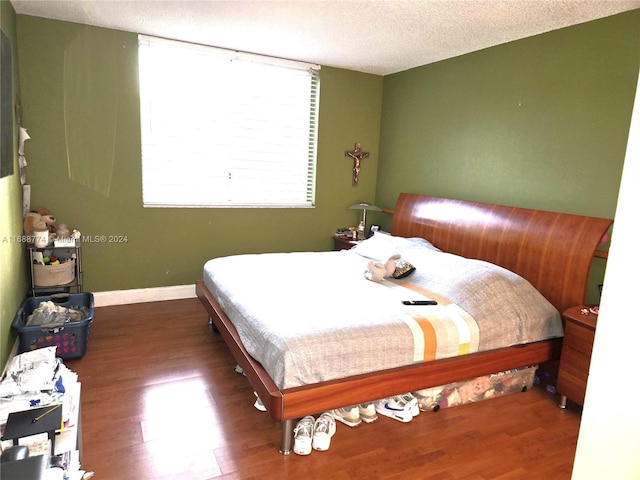 bedroom with dark hardwood / wood-style flooring and a textured ceiling