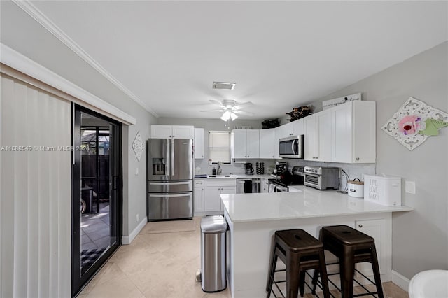 kitchen with kitchen peninsula, white cabinets, a breakfast bar area, and stainless steel appliances