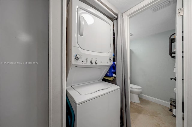 washroom featuring stacked washer and clothes dryer and light tile patterned floors