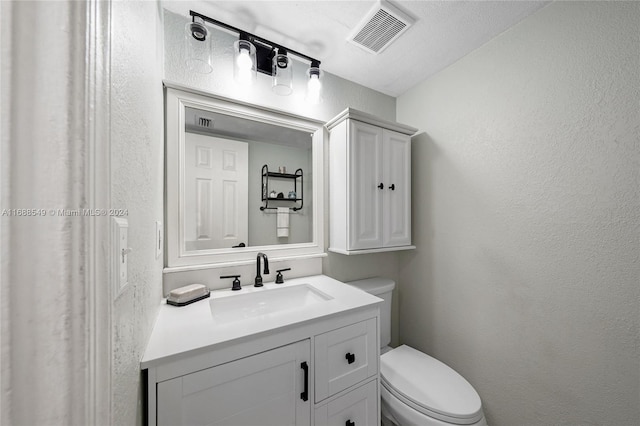 bathroom featuring toilet, vanity, and a textured ceiling