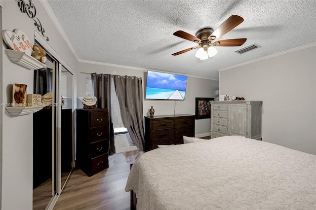 bedroom with ornamental molding, ceiling fan, a textured ceiling, a closet, and light wood-type flooring