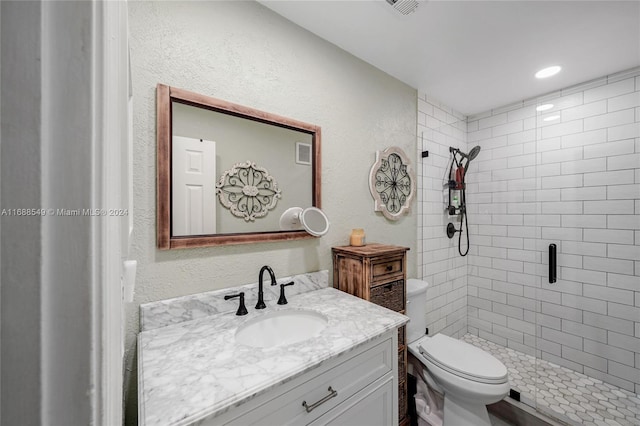 bathroom featuring vanity, toilet, and tiled shower