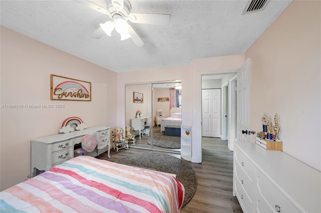 bedroom featuring ceiling fan, dark hardwood / wood-style floors, a closet, and a textured ceiling