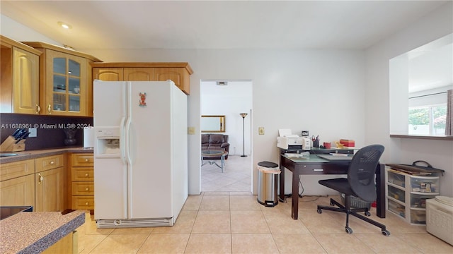 kitchen featuring tasteful backsplash, white fridge with ice dispenser, and light tile patterned flooring