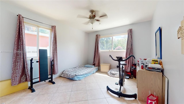 exercise area with ceiling fan and light tile patterned flooring